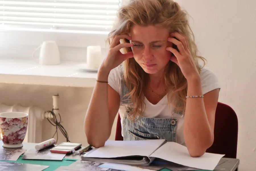 Zdjęcie przedstawia próbę stolikową do spektaklu „Ifigenia ze Splott”. Z łokciami na stole siedzi intensywnie myśląca Agnieszka Skrzypczak. Palce obydwu dłoni aktorki dotykają jej skroni. Jej oczy są skierowane poniżej obiektywu na fotografie a usta są lekko otwarte. Na stole, nad którym pochyla się aktorka znajduje się zeszyt, długopis, telefon, kubek w kwiaty i czarno-białe zdjęcia.