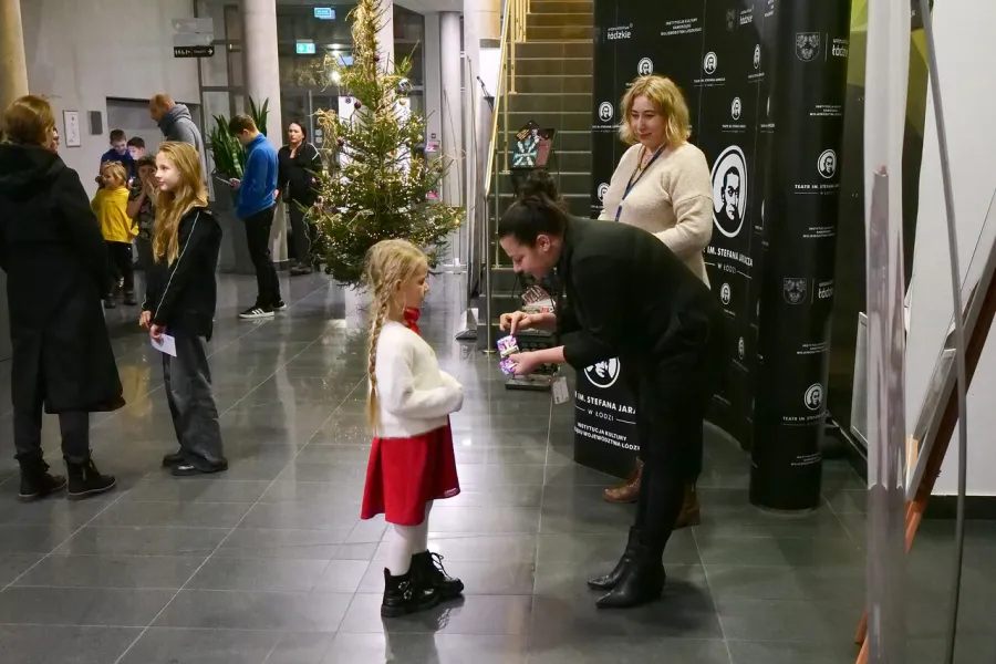 zdjęcie przedstawia widzów oczekujących na wejście na salę teatralną, na foyer w Miejskim Centrum Kultury w Bełchatowie 