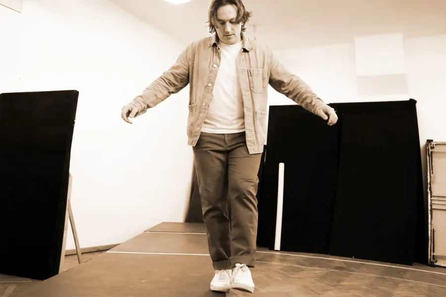 Zdjęcie przedstawia aktora Konrada Krupińskiego, który chodzi po kawędzi podestu. 