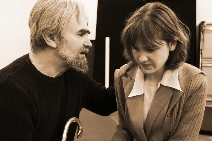 zdjęcie przestawia dwoje aktorów: Dariusza Bereskiego i Szantal Strzelińską. Aktorzy siedzą na podeście. Aktorka ma wystraszoną minę i siedzi przygarbiona jakby się bała. 