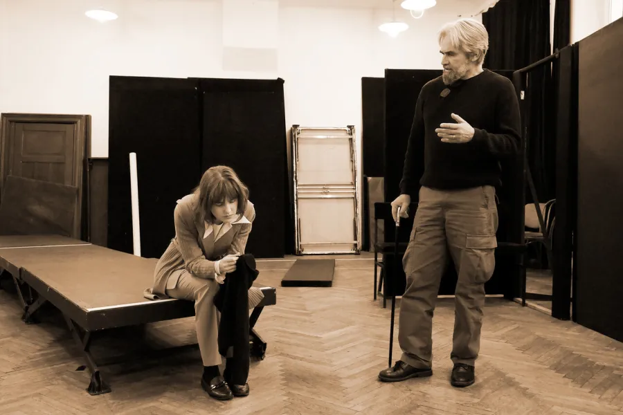 zdjęcie przestawia dwoje aktorów: Dariusza Bereskiego i Szantal Strzelińską. Aktorka siedzi na podeście, w rękach trzyma czarny materiał. Aktor stoi po jej lewej stronie. W prawej ręce trzyma laskę. 