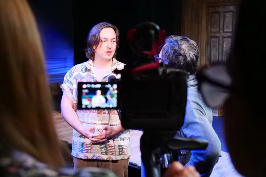 Zdjęcie z próby medialnej spektaklu „Zamiana". Na zdjęciu w nieostrości widać aktora Konrada Krupińskiego, który jest widoczny na podglądzie kamery. 