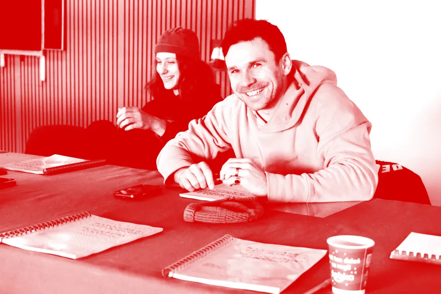 Zdjęcie przedstawia pierwszą próbę spektaklu „Morderstwo w hotelu”. Na zdjęciu widać dwójkę aktorów Natalię Klepacką, która jest oparta na krześle i się śmieje oraz Krzysztofa Wacha, który śmiejąc się patrzy prosto w obiektyw aparatu. Na zdjęcie został nałożony czerwony filtr.