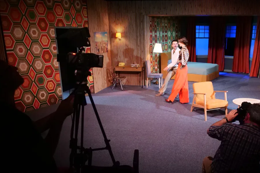 próba medialna spektaklu „Morderstwo w hotelu", na zdjęciu: Krzysztof Wach, Natalia Klepacka stojący na scenie. Na widowni stoi kamera, fot. Marcin Nowak