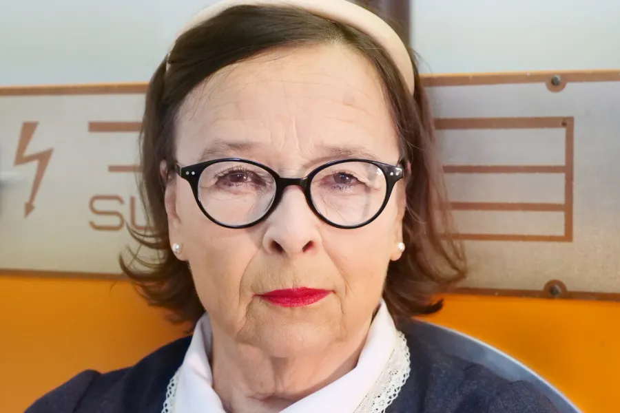sesja zdjęciowa do spektaklu, na zdjęciu: Bogusława Pawelec w stroju pokojówki. Jest to zdjęcie portretowe. Aktorka ma czerwone usta i opaskę na włosach oraz okrągłe korekcyjne okulary, fot. Marcin Nowak