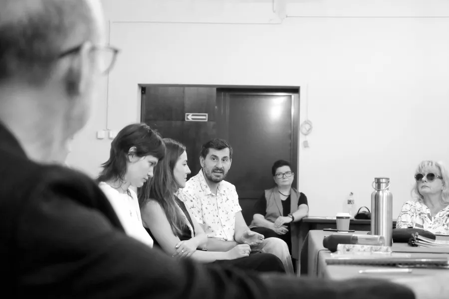 pierwsza próba spektaklu „Czas na wielki numer", na zdjęciu na pierwszym planie w lewym dolnym rogu zdjęcia siedzi tyłem dyrektor Paweł Łysak, dalej widać reżyserkę spektaklu Barbarę Bendyk, scenografkę WIktorię Kubat oraz kierownika literackiego Pawła Sztarbowskiego, który coś tłumaczy. Na zdjęcie nałożony jest czarno-biały filtr, fot. Marcin Nowak 