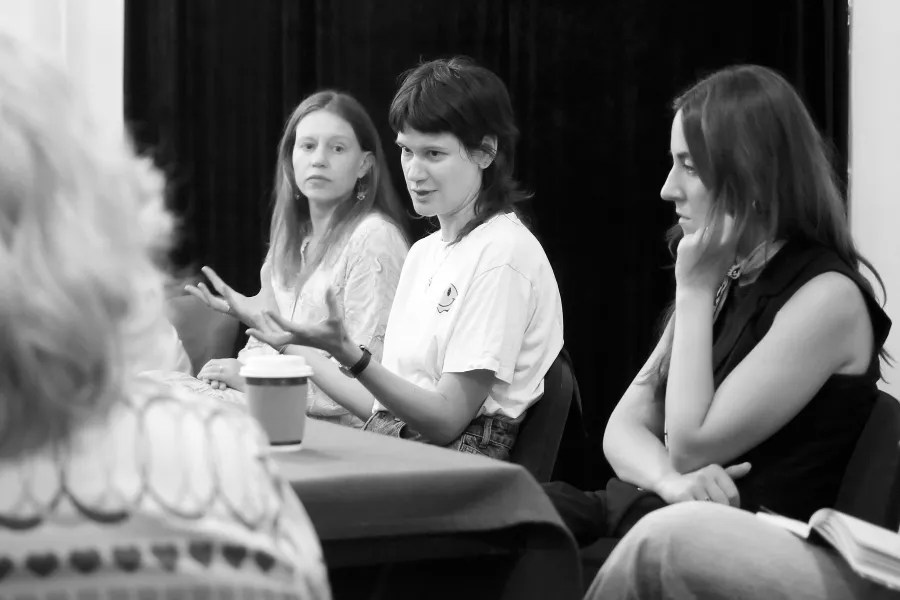 pierwsza próba spektaklu „Czas na wielki numer", na zdjęciu siedzące przy stole od lewej aktorka Matylda Paszczenko, reżyserka Barbara Bendyk, która gestykuluje oraz scenografkę Wiktorię Kubat. Na zdjęcie nałożony jest czarno-biały filtr, fot. Marcin Nowak 