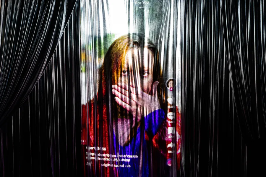 Zdjęcie ze spektaklu „Czas na wielki numer". Na fotografii widać projekcję, która wygląda jak rolka na mediach społecznościowych. Na wideo jest kobieta, która zakrywa ręką usta