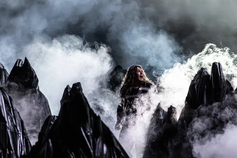 Zdjęcie przedstawia góry, wokół nich jest dużo dymu imitującego mgły. Pośród gór widać niewyraźnie aktorkę Milenę Lisiecką. Autorką zdjęcia jest Natalia Kabanow